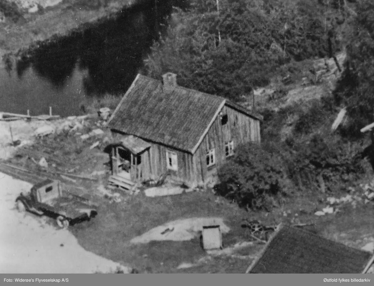Flyfoto  av Bergby gård (Fossengen) i Varteig 1959, bakerst til venstre er smie og verksted, kjeller, bryggerhus, bu, våningshus, og vedskjul, fjøs og stall og låve foran til venstre.
Bilde nummer to er utsnitt fra tunet med bilde av lastebil.