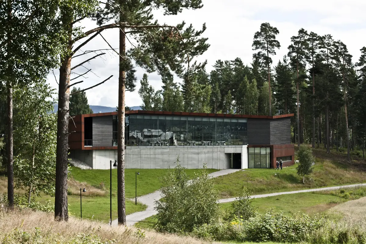 Moderne museumsbygning med trær rundt. Bygget har store glassvinduer