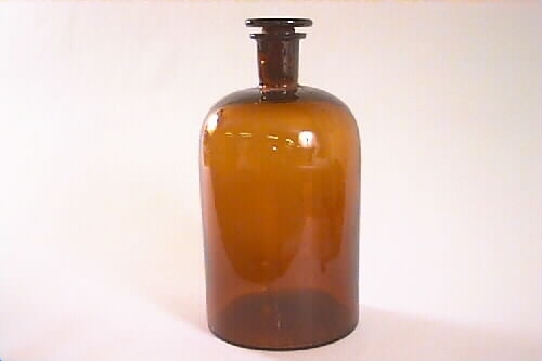 Brun flaska av glas. Cylinderformad, upptill rundad och avslutad med en 6 cm hög hals med glaspropp (b).