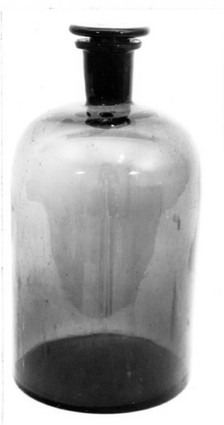 Brun flaska av glas. Cylinderformad, upptill rundad och avslutad med en 6 cm hög hals med glaspropp (b).