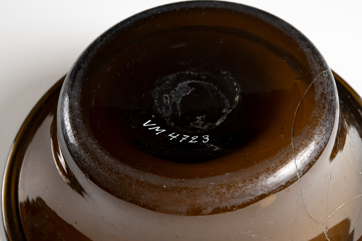 Rund, välvd botten och utsvängd upptill av brunt glas. Lagad.