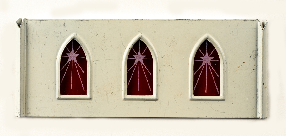 Juldekoration (änglaspel) i form av en kyrka. Vita väggar med grönt tak och spira, röd plast för fönster. Fungerar som ett änglaspel.

Föremålet är omonterat i sin tillhörande pappkartong.