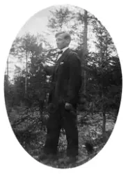 Vykort med porträtt av en man ute i naturen. På baksidan stå