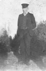 Vykort med porträtt av en ung man utomhus. På baksidan står 