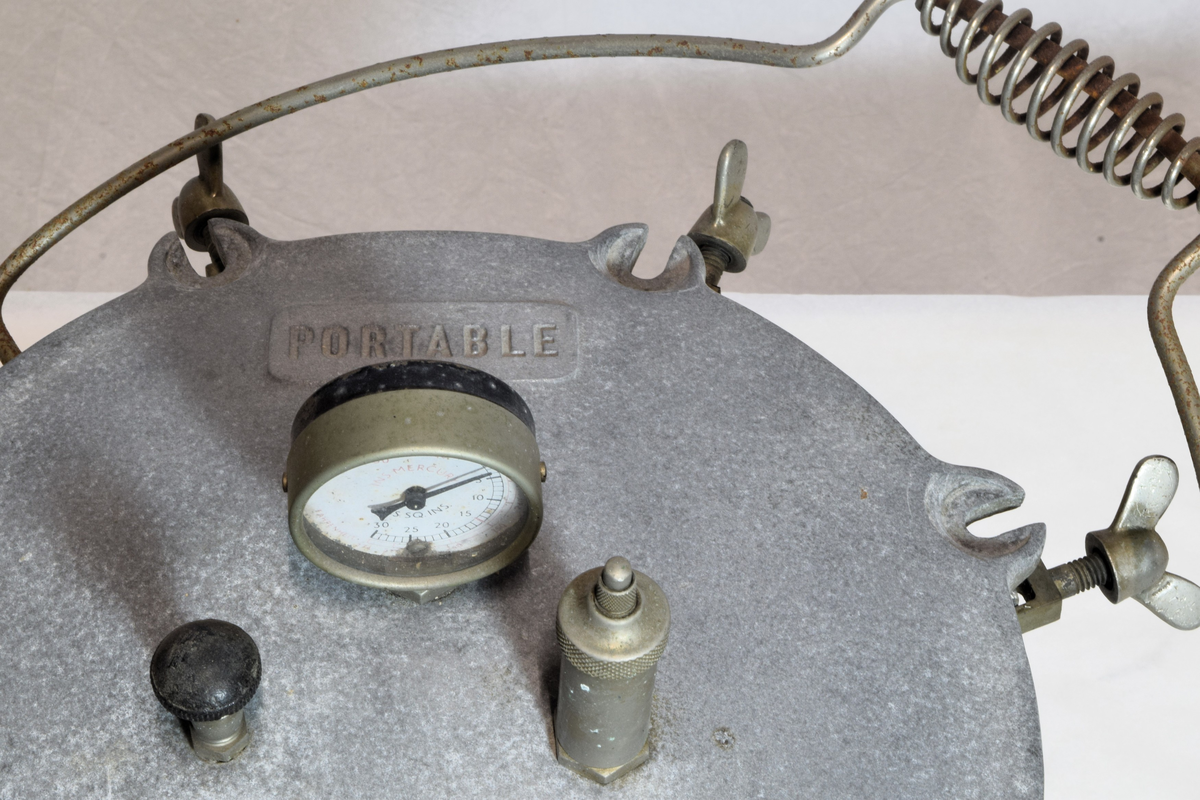 Består av 3 deler: selve aluminiumskjelen med 8 skruhoder, lokk med 8 ører som passer til skruene, trykkmåler samt to ventiler (trykkventiler). Inni en kurv. Lokket melert. Autoklaven ble brukt til sterilisering av legemidler og utstyr som måtte være sterile for produksjon av legemidler.