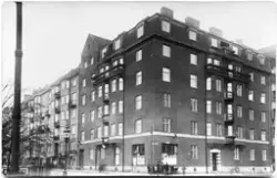 Vykort med en tegelbyggnad i ett stadskvarter, troligen i St