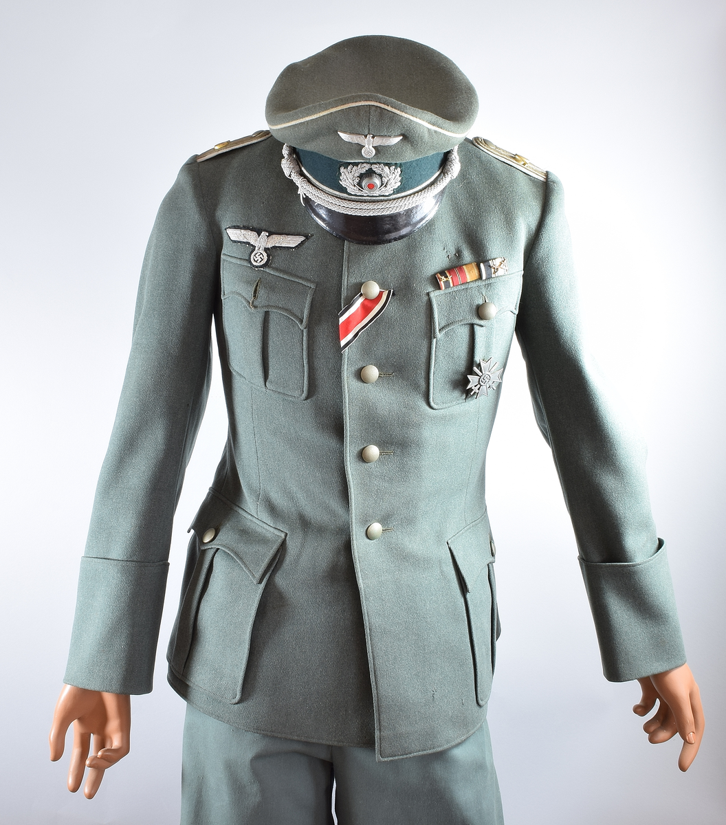 Offiseruniform for den tyske hær, infanteri. Består av uniformsjakke i grønn fin ull og innvendig silkefor med tilhørende hatt (buksen er ikke original). Den tyske riksørnen med hakekors er sydd på høyre bryst.