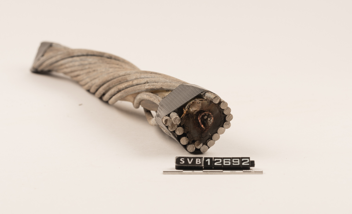 En halv meter lang bit av en skadet fiberkabel. Kabelen består av flere lag , og er 3,5 centimeter tykk i ytre diameter (inkludert integrert strømforsyning).  Kabelens oppbygging er:
•	Innerst ligger optiske fibre som leder lyssignalene
•	Fibrene ligger i en gel i et rør av plast
•	Utenpå dette ligger armeringstråder av stål
•	Disse er omgitt av kobberbånd som leder strøm
•	Neste lag er beskyttelse av polyethylen
•	Utenpå dette er det spunnet kraftig stålarmering
•	Ytterst er et lag av tjæreinnsatt jute 

Denne 1/2 meter lange biten av den ca. 200 m lange skadde delen, har mistet det ytterste laget og er vridd. Kabelen var aldri totalt brutt. Den innerste delen var hel. Ansatte i Space Norway skar av denne kabelbiten. De festet tape rundt begge ender slik at stålarmeringen ikke skulle gå fra hverandre. Museets konsevator erstattet denne tapen med en som var mer solid.
