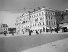 Linköping en solskensdag i början av förra seklet. Ännu skulle det dröja innan torget smyckades med Carl Milles folkungamonument. Stora hotellet känns lätt igen in i vår tid. Bilden har lämnat oss daterad 1921 men det finns skäl att betvivla uppgiften. Den så kallade hotellflygeln, hotellets utbyggnad, ser misstänkt nybyggd ut i avsaknad av fasadputs. Huskroppen togs i bruk under hösten 1905. En rimlig datering torde således vara 1905, möjligtvis 1906.