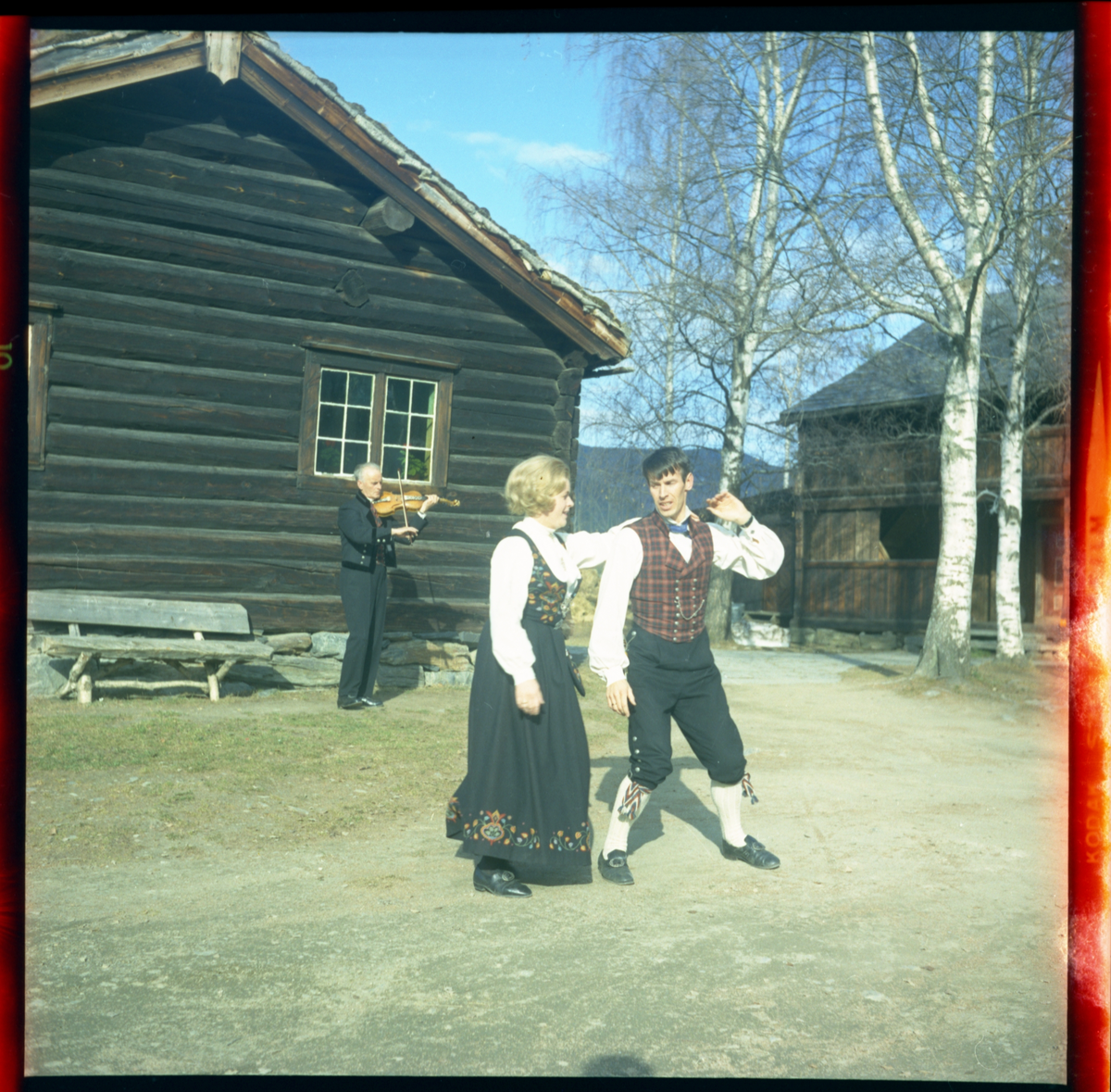 Spelemann og dansarar utanfor Skattebustogo på Valdres Folkemuseum 1970.