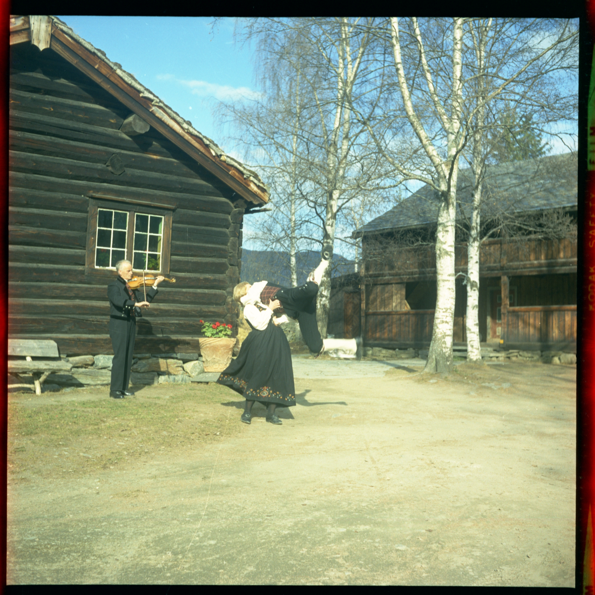 Spelemann og dansarar utanfor Skattebustogo på Valdres Folkemuseum 1970.