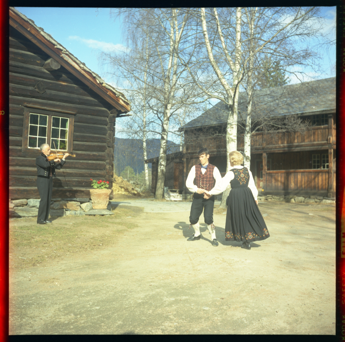 Spelemann og dansarar utanfor Skattebustogo på Valdres Folkemuseum 1970.