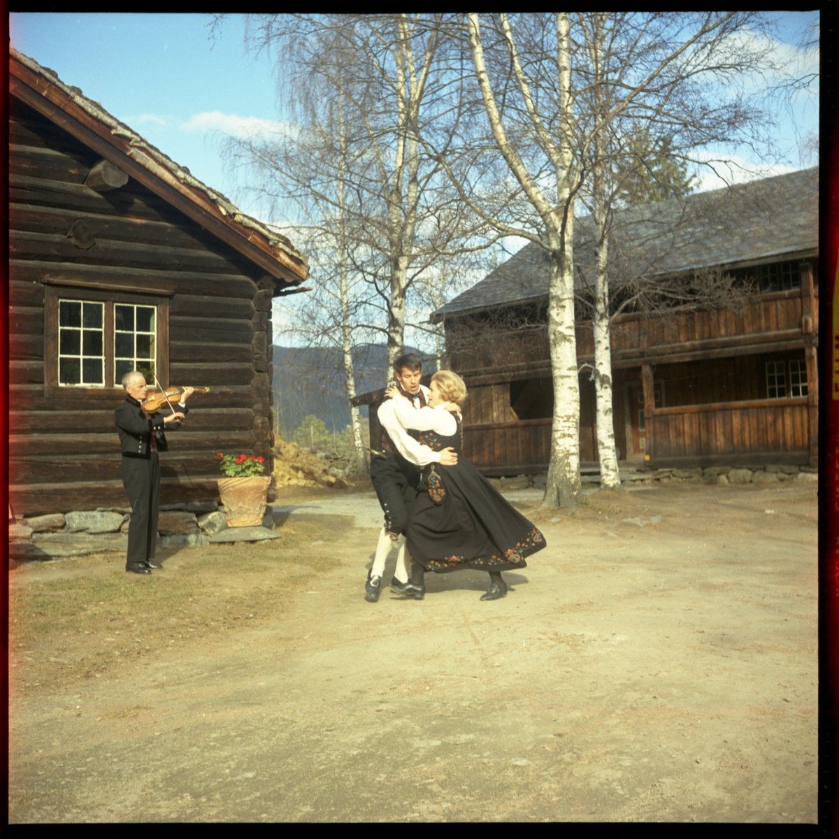 Spelemann og dansarar utanfor Skattebustogo på Valdres Folkemuseum 1970.