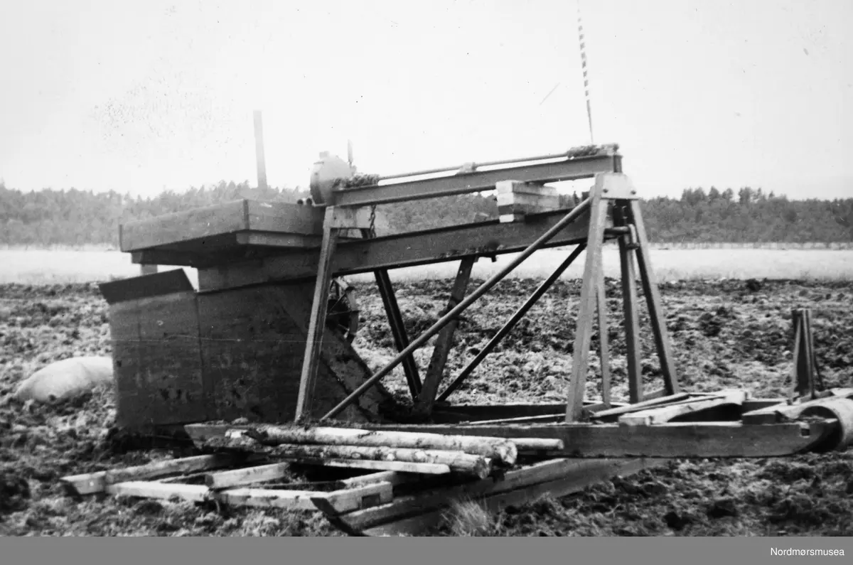 Landbruksmaskin. Maskin for produksjon av rør? Ukjent hvor og når, men trolig i Nord-Norge. Det er Ny Jord som har tatt fotografiet. Et foto fra fotosamlingene til Nordmørsmusea AS og Norsk myrmuseum.