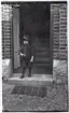 En liten pojke i 4-5-årsåldern i dörröppningen till ett hus på regementsområdet, (trol.) I11. 
Ev. sonen till en stamanställd.