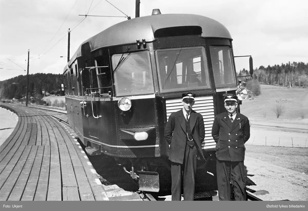 Lokaltoget Moss - Sarpsborg, ca. 1955. Skinnebuss, dieseldrevet. Skinnebussen står ved Onsøy jernbanestasjon, Østfoldbanens vestre linje, 86, 51 km. Fra venstre: lokomotivfører NN og overkonduktør Johannes Kilde.