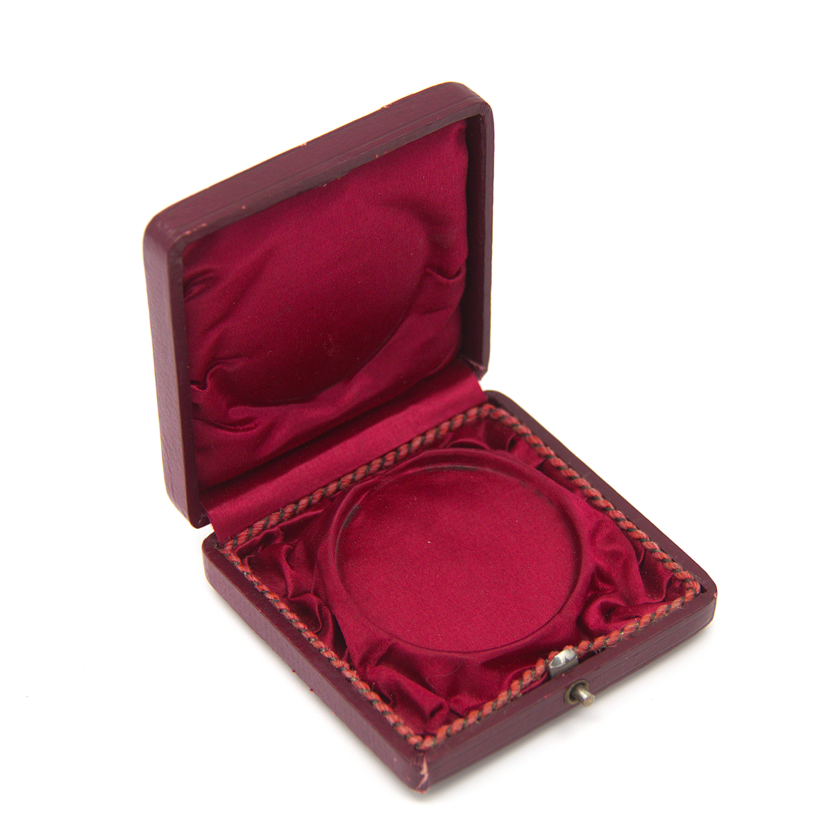 Medalj ur Ahlgrens medaljsamling. Tilldelades Ahlgrens Tekniska Fabrik i Lübeck 1895 (´för framstående prestation´). Guldfärgad. Asken är i burgundyröd trä och har insidan klädd med ett sidenliknande material samt omslag av läderimitation (papper). På locket finns en fastklistrad äldre lapp med handskriven information om plats och datering: "Lübeck 1895". Tidigare märkning: 2a.