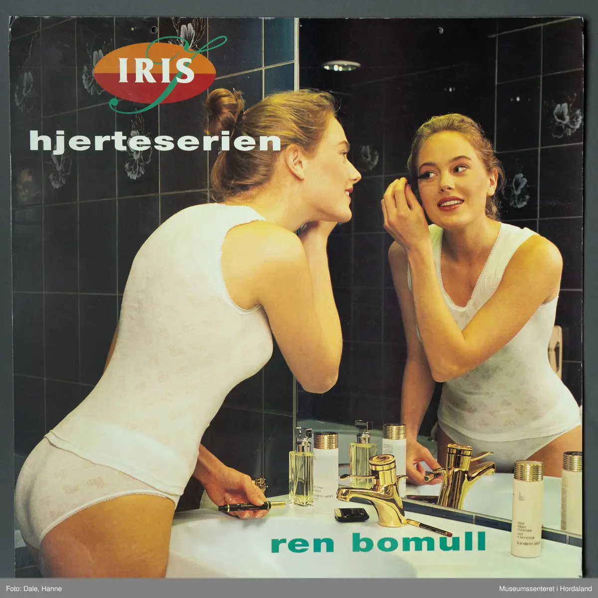 Kvinne i kvitt undertøy med hjartemønster, som sminkar seg framfor ein spegel.