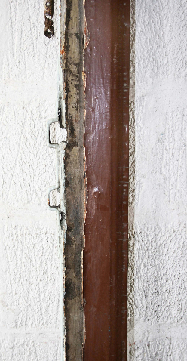 Insidan ljusgrå med 3 speglar. Utsidan brun med dekorerade fält, upptill med bågar, i mitten med rombiska figurer samt nedtill med räfflor och halvrunda stavar mellan lister. Automatisk stängningsanordning påsatt. Mässingstycke. Extra lås. Firmadekaler "Skånska Cementgjuteriet" och "Bofors Nohab". Smalt tvärställt fönster med dekor av pilar och bågar. B 1440 H 390 mm. Del av karm samt dörrfoder medföljer. Okänd härkomst.