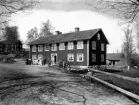 Bostadshus vid grusväg på okänd plats i Kronobergs län. Många människor uppställda framför huset.