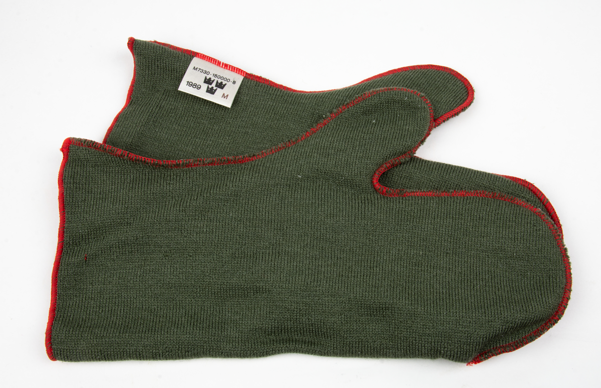 Ett par tumhandskar, fältuniformsystemet 90. Ytterhandsken är förstärkt med vitt gerskin. På handsken sitter remmar samt kardborreband för åtspänning samt remmar med metalring för fastsättning i plagg. I handsken urtagbara fodervantar.