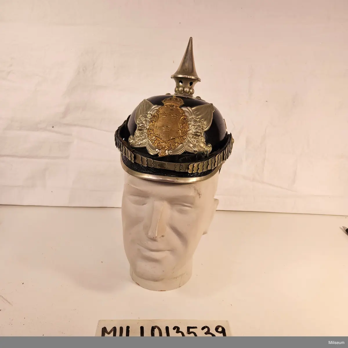 Kask m/1887 av pressat läder och med förnicklade detaljer.