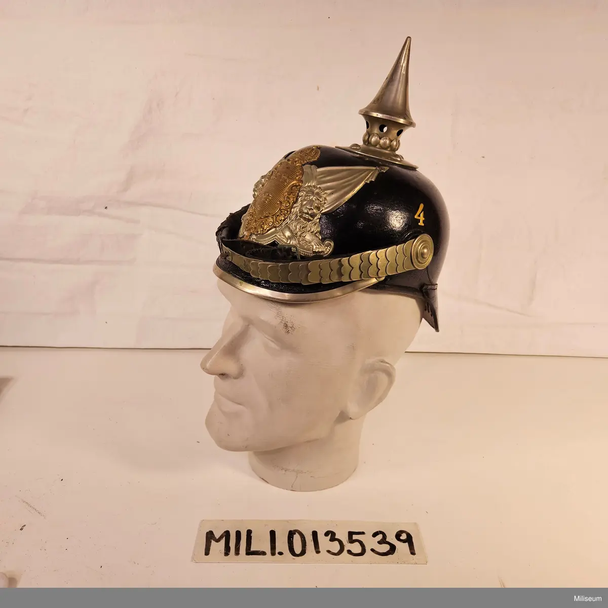 Kask m/1887 av pressat läder och med förnicklade detaljer.