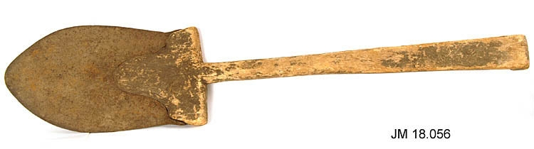 Spade av trä och metall. Skaftet har troligtvis varit bemålat med svart färg. Saknar dekor.