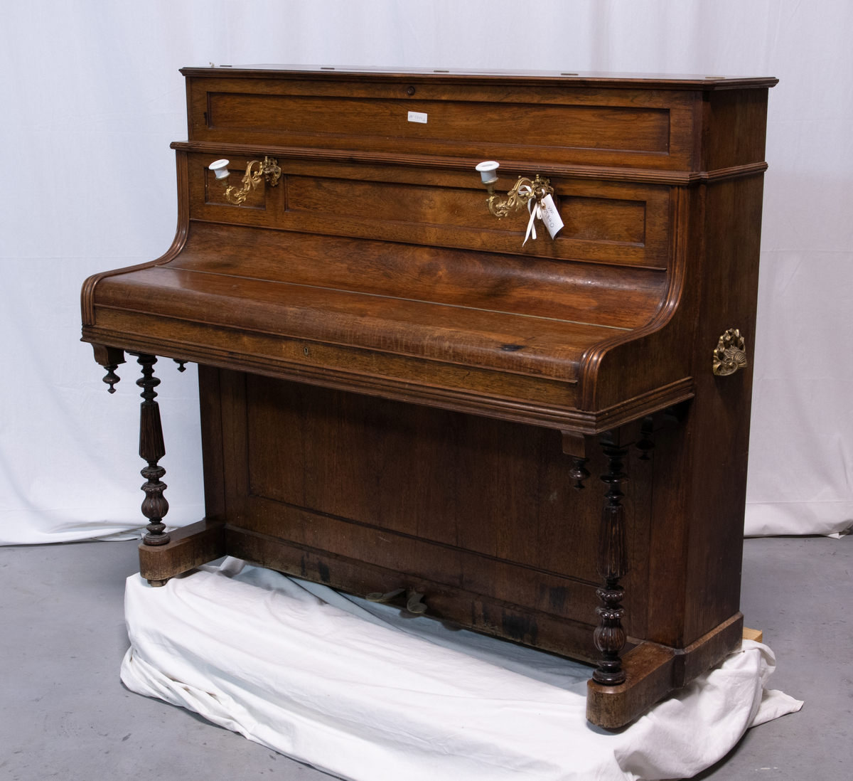 Piano med stående pianokasse i finert jakaranda med pianolokk, lite topplokk og to dreide, fremre konsollben. På sidene er to bærehåndtak i messing. Over pianolokket er to lysholdere i messing og porselen. To pedaler.