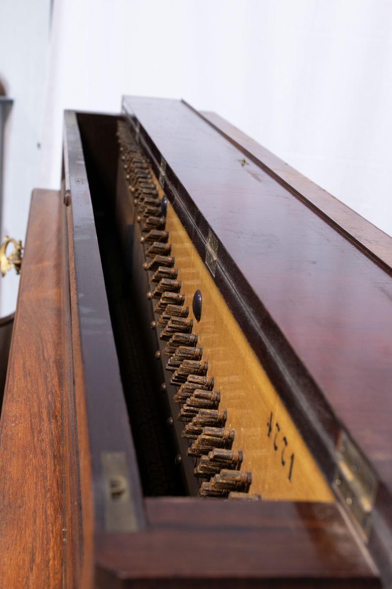 Piano med stående pianokasse i finert jakaranda med pianolokk, lite topplokk og to dreide, fremre konsollben. På sidene er to bærehåndtak i messing. Over pianolokket er to lysholdere i messing og porselen. To pedaler.