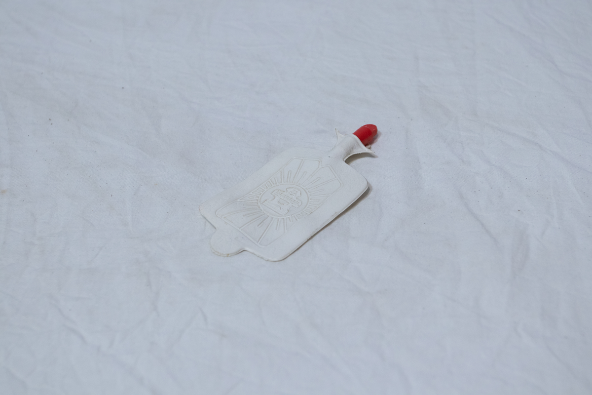 Stellebord til dukke. Rødmalt trekonstruksjon av runde pinner, tappet sammen i kryss i bena. Kan slås sammen. Badekar naglet fast i trerammen, laget av plast/vinyl. Badekaret har propp med slange i bunnen. Stellematte kan legges oppå badekaret, denne er laget i bomull. Stellematte stives av ved to lærstropper under, disse er spikret fast. Påfestet bærhåndtak i toppen av metall, skrudd med to skruer. På ene siden ett stykke med lysblå plast med tre lommer, hele stykket og lommene er kantet med rødrutete stoff.