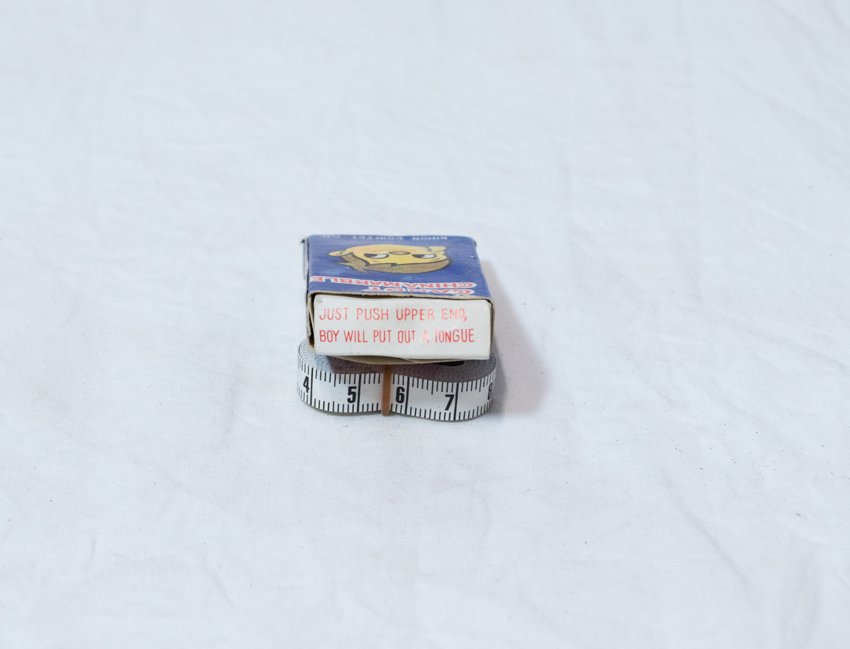 Stellebord til dukke. Rødmalt trekonstruksjon av runde pinner, tappet sammen i kryss i bena. Kan slås sammen. Badekar naglet fast i trerammen, laget av plast/vinyl. Badekaret har propp med slange i bunnen. Stellematte kan legges oppå badekaret, denne er laget i bomull. Stellematte stives av ved to lærstropper under, disse er spikret fast. Påfestet bærhåndtak i toppen av metall, skrudd med to skruer. På ene siden ett stykke med lysblå plast med tre lommer, hele stykket og lommene er kantet med rødrutete stoff.