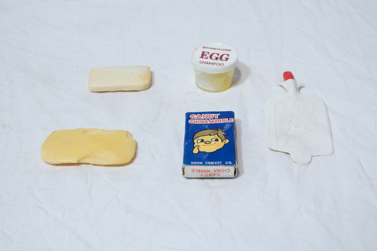 Stellebord til dukke. Rødmalt trekonstruksjon av runde pinner, tappet sammen i kryss i bena. Kan slås sammen. Badekar naglet fast i trerammen, laget av plast/vinyl. Badekaret har propp med slange i bunnen. Stellematte kan legges oppå badekaret, denne er laget i bomull. Stellematte stives av ved to lærstropper under, disse er spikret fast. Påfestet bærhåndtak i toppen av metall, skrudd med to skruer. På ene siden ett stykke med lysblå plast med tre lommer, hele stykket og lommene er kantet med rødrutete stoff.