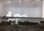 Det är dags att ge sig iväg ut för nattens fiske. Några båtar har redan kommit ut, andra lastar ännu i fiskedonen. Alla verkar fiska samtidigt, vilket var rätt brukligt. Man fiskade jämt när vädret var gott och det inte var något akut med skörd e dyl. Fisk var basmat som åts till de flesta av dagens måltider, särskilt strömming. Man saltade in tunnvis med fisk för årets behov. Man visste aldrig när man kunde komma ut nästa gång för vädret, så det gällde att passa på. Dessutom var man flera i ett båtlag och då måste man hjälpas åt, det gick inte an att någon hade annat för sig. I regel hade man också strikta roller i båten som man inte bytte, var och en måste utföra sin uppgift. Se Nr 409.