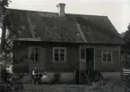 Denna lilla gård kom till 1910 då Arvid Persson född 1877 från Mattsarve köpte jord av Lars Per Hallander Hallbjäns, vilken sålde bort hela denna gårdspart i smålotter. Arvid var gift 1903 med Hanna Byström född 1871 från Alskog och de bebyggde boplatsen. Detta bostadshus byggde de 1912 och byggde till det 1924. Huset är uppfört av resvirke med liggande panel och taket är täckt med spån. Det ser lite äldre ut än 4 år gammalt, men kan knappast vara det.

Det är sannolikt Arvid 39 år och hans fru Hanna 45 år som sitter mot husväggen. Sonen Ragnar 12 år står nog bredvid trappan, men den som står på den är okänd.