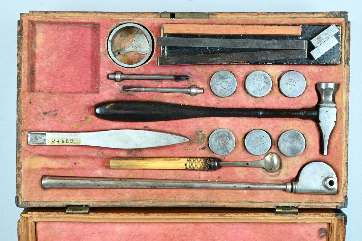 Reagensbestick för blåsrörsanalys, i fodral av trä. Lösa delar: isärtagbart blåsrör av silver, troligen av Bergmans typ, två blåsrörsmunstycken av silver, liten degel av silver med vridbart lock och skaft av trä, hammare med skaft av ebenholts, ring av stål till kross, sex reagensdosor av silver, med lösa lock med kemiska tecken, enligt Scheffer-Bergman jämte reagens (kalkspat, gips, borax (?), salpeter (?), alkalisalt), pincett av silver med "kattfot" och "B 2" END B=S:t Erik? (=1784), två stavmagneter med två armeringsjärn och trästav i fodral av papp och trä, fodral, skjutlåda, blåsrör av mässing av Berzelius typ. Kvadratisk stöd av stål och nyckel till fodralet och skjutlådan saknas. Måtten avser fodralet.