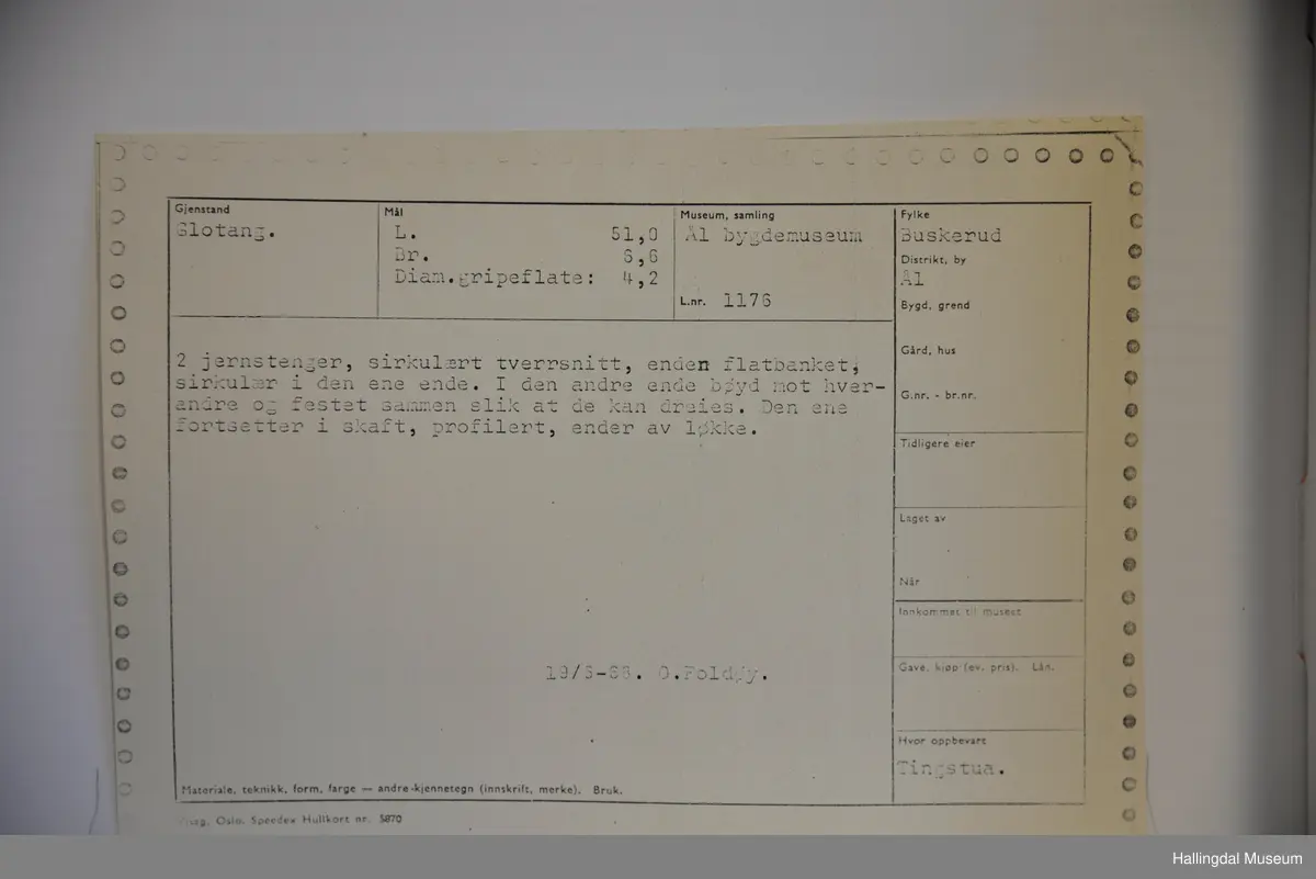 2 jernstenger, rundt tverrsnitt, enden flatbanket, sirkulær i den ene enden. I den andre enden bøy mot hverandre og festet sammen slik at de kan dreie. Den ene fortsetter i skaft, profilert, ender i løkke.
