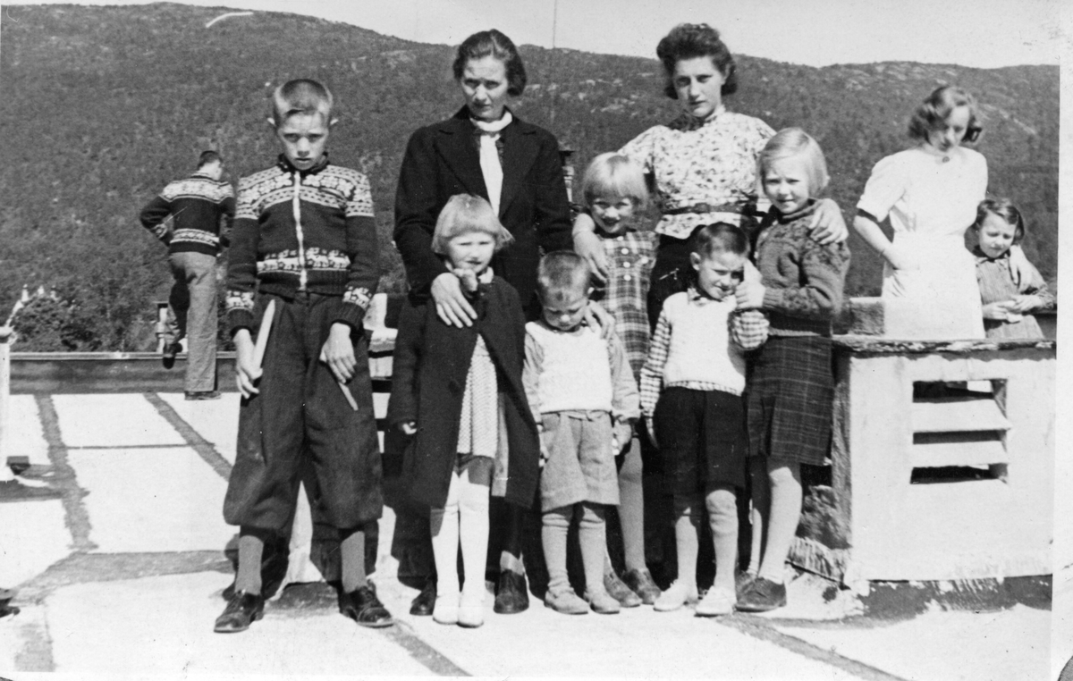 Ei mor med sine seks born og ei ung kvinne på taket på Storetveit skole. Ei sjukepleiar med eit barn i bakgrunnen.