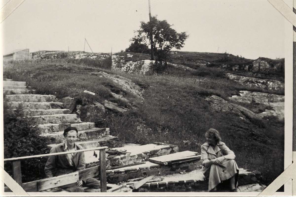 Telavåg, gjenreisinga. Ein mann og ei dame som sit ved ei utbrent betongtrapp til eit rasert hus.