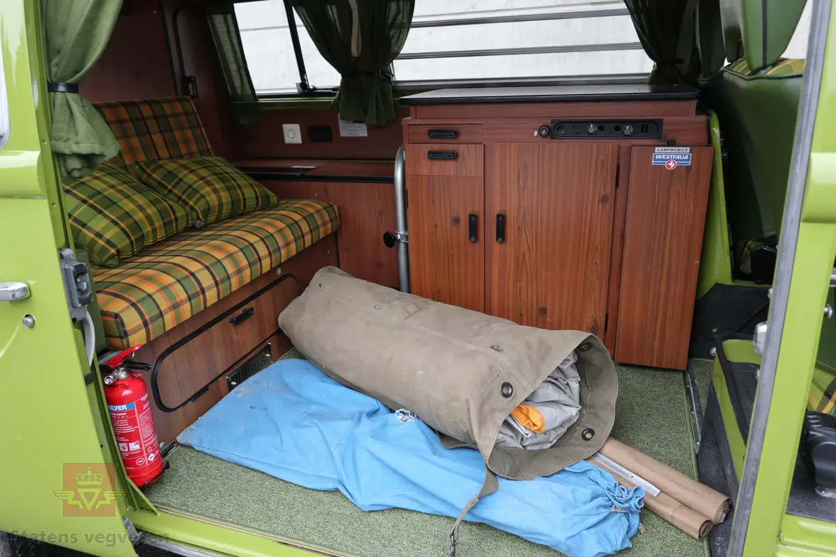 Volkswagen Type 2 Westfalia. Kombinert personbil og campingbil (med forhøyet tak). Grønn (L 63 H Taiga Green) og hvit utvendig. Bilen er innredet for camping og interiøret er grønt med innslag av svart, gult og oransje. Taket kan slås opp for å gi bedre plass for overnatting. Bilen har fire hjul og er toakslet med trekk på bakre. Bensindrevet firesylindret firetakts boxer motor (type GD) med et sylindervolum på 1970 cm3 og en effekt på 70 hk - 51 kW. Motornummer er GD 24 260 (originalmotoren). Motoren har innsprøytning, er luftavkjølt, og sitter bak på bilen. 4-trinns manuell girkasse med spak i gulvet. Vann- og strømtilkobling samt utlufting av gassdrevet kjøleskap er plassert på førersiden. Antall sitteplasser er fire. Dekkdimensjon rundt om er 185 R 14 C. Bilen har hengerfeste og bensinvarmer. I USA ble disse bilene (som denne) levert med innsprøytingsmotor og ikke to forgassere som de ble levert med i Europa. Kilometerstand er 2322 km (speedometeret ble byttet under restaureringen). Fortelt følger med bilen.