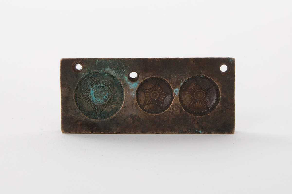 Støpeform for støping av tre stettknapper i ulik størrelse, med stjerneformet rosett i forskjellige former. Støpeformen er av bronse og i fem deler.