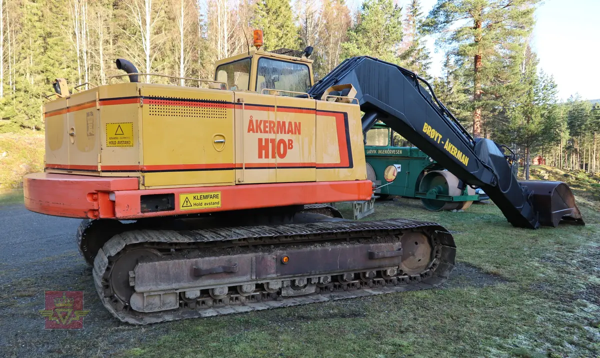 Åkerman H10B gravemaskin. Beltegående. Gul, rød, og svart. Merking fra produsent og første bruker. Maskina har en dieseldrevet Volvo Penta TD61ACE motor, den yter 166 Hk (122 kW). Motoren er 6-sylindret, 4-takt, med vannavkjøling, direkte innsprøytning og turbo. Det elektriske systemet er 24V. Drivstofftanken rommer 340 liter. Lydnivået er 77dB (målt 10 meter fra maskinen). Serienummer er 2632.
Maskinen har gått 10.000 arbeidstimer.