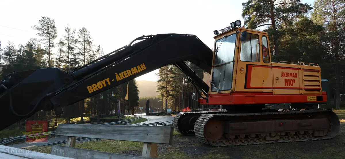 Åkerman H10B gravemaskin. Beltegående. Gul, rød, og svart. Merking fra produsent og første bruker. Maskina har en dieseldrevet Volvo Penta TD61ACE motor, den yter 166 Hk (122 kW). Motoren er 6-sylindret, 4-takt, med vannavkjøling, direkte innsprøytning og turbo. Det elektriske systemet er 24V. Drivstofftanken rommer 340 liter. Lydnivået er 77dB (målt 10 meter fra maskinen). Serienummer er 2632.
Maskinen har gått 10.000 arbeidstimer.