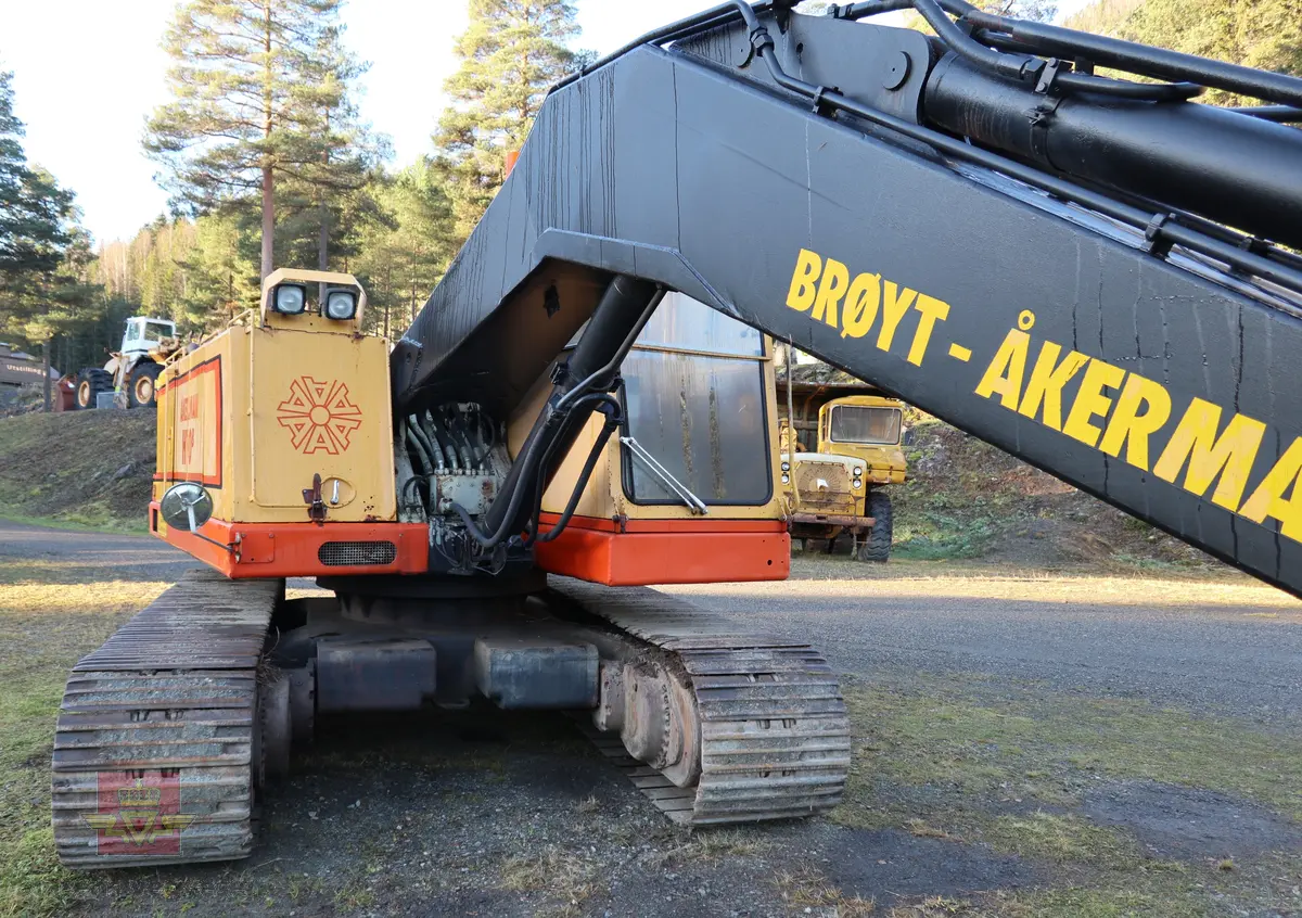 Åkerman H10B gravemaskin. Beltegående. Gul, rød, og svart. Merking fra produsent og første bruker. Maskina har en dieseldrevet Volvo Penta TD61ACE motor, den yter 166 Hk (122 kW). Motoren er 6-sylindret, 4-takt, med vannavkjøling, direkte innsprøytning og turbo. Det elektriske systemet er 24V. Drivstofftanken rommer 340 liter. Lydnivået er 77dB (målt 10 meter fra maskinen). Serienummer er 2632.
Maskinen har gått 10.000 arbeidstimer.