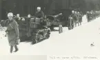 Trupp i vintermundering följer en 10,5 cm kanon m/1934 dragen av en artilleritraktor på en snöig skogsväg.
