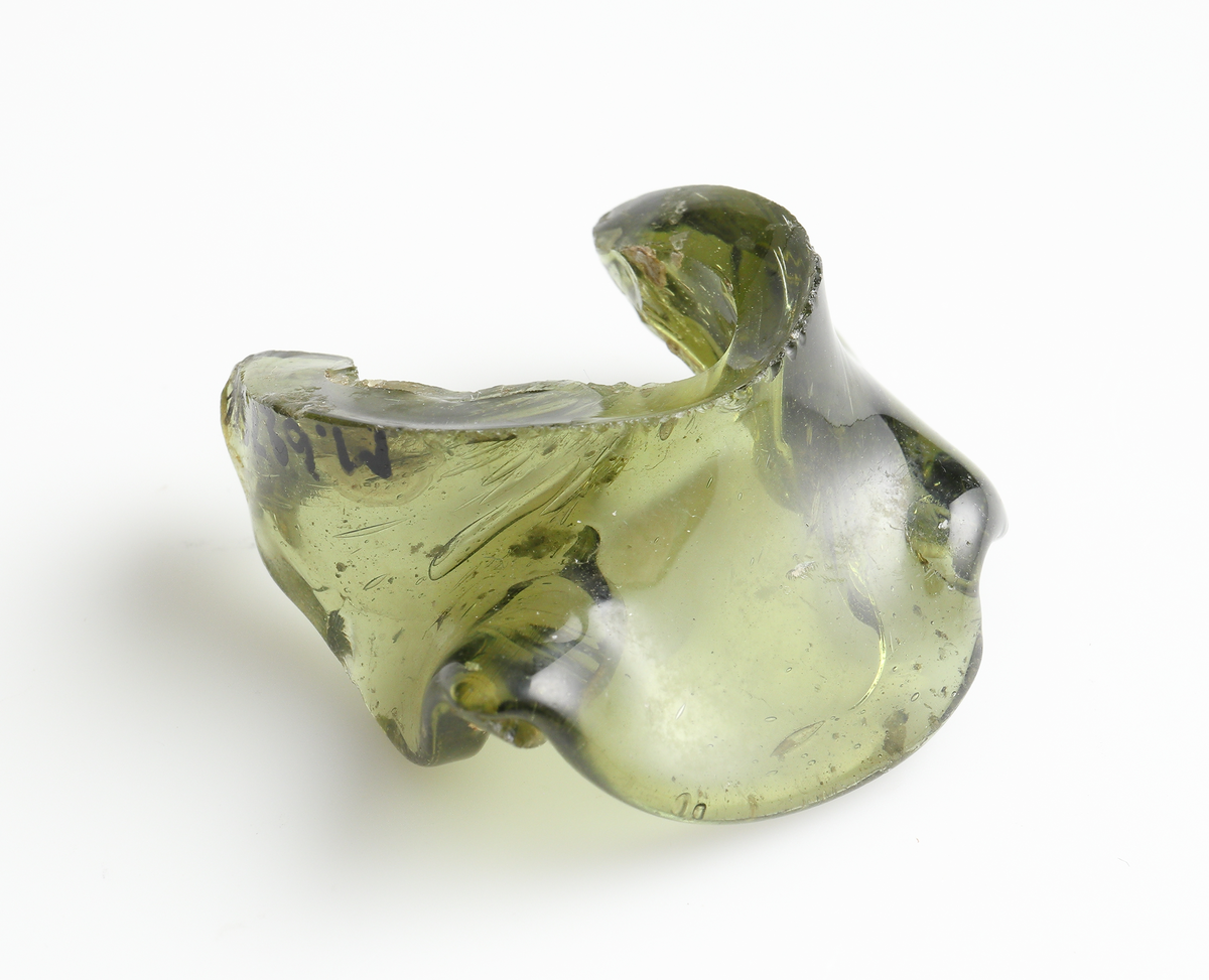 Två veckade glasfragment av grön glasmassa. Möjligen en form av mynning, eller en veckad krage till en flaska?