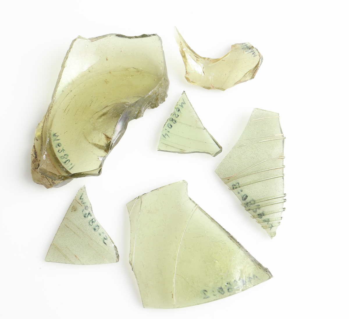 Totalt 6 fragment av en (?) bägare eller kanna (?) i gröntonad glasmassa med pålagda glastrådar. Se ex. SKALK nr 3, 2005, s.13.
