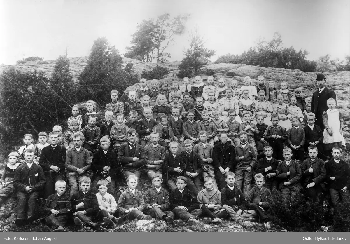 Klemsdal skole i Varteig, gruppebilde av skoleelever og lærer 1895.
Noen av guttene har Napoleon-positur (ene armen stukket inn i i jakka).