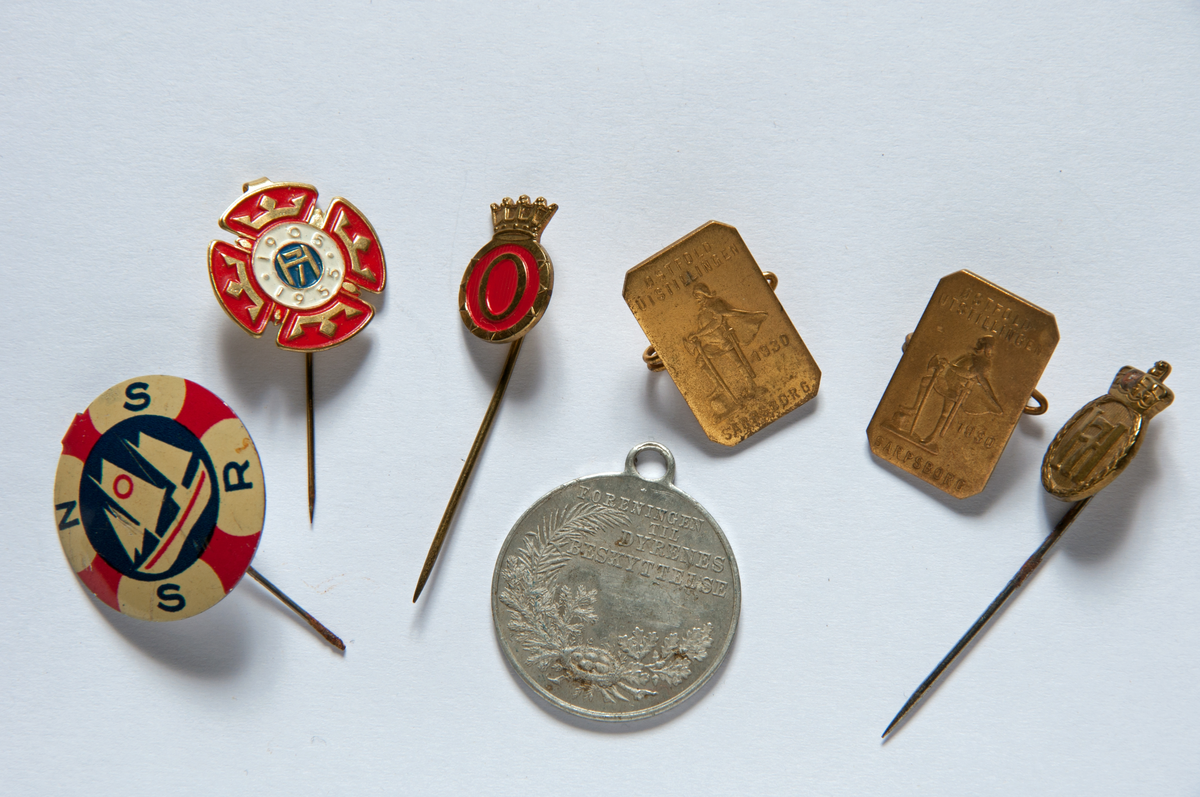 Samling jakkermerker, 7 stk: Ver god mot dyrene, 2 stk frå Østfoldutstillingen 1930, H7, Olavmerke (kronprins), Redningsselskapet, 1905-1955.