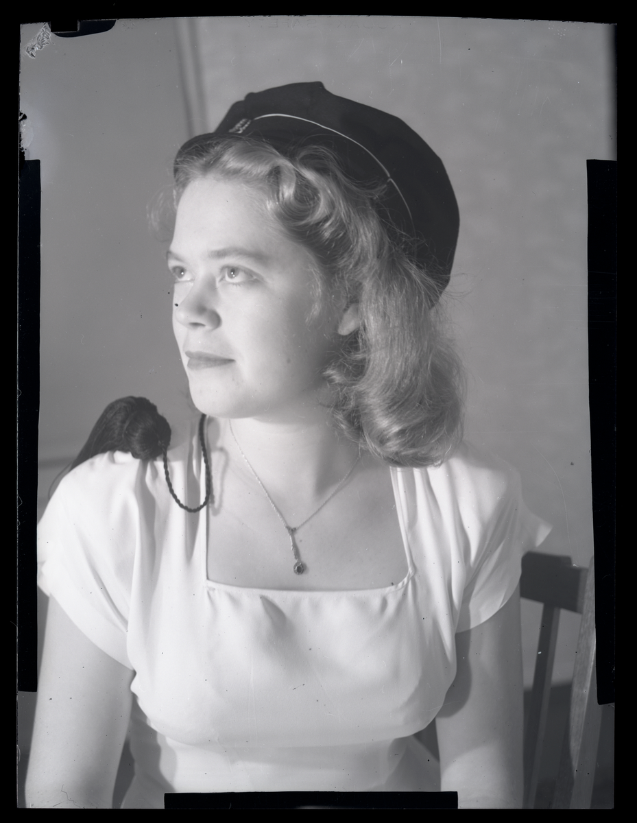 Studioportrett av  ung kvinne med russehatt, ukjent person. Antageligvis fra 1950-tallet.

Påskrift på konvolutt negativet lå i: 10